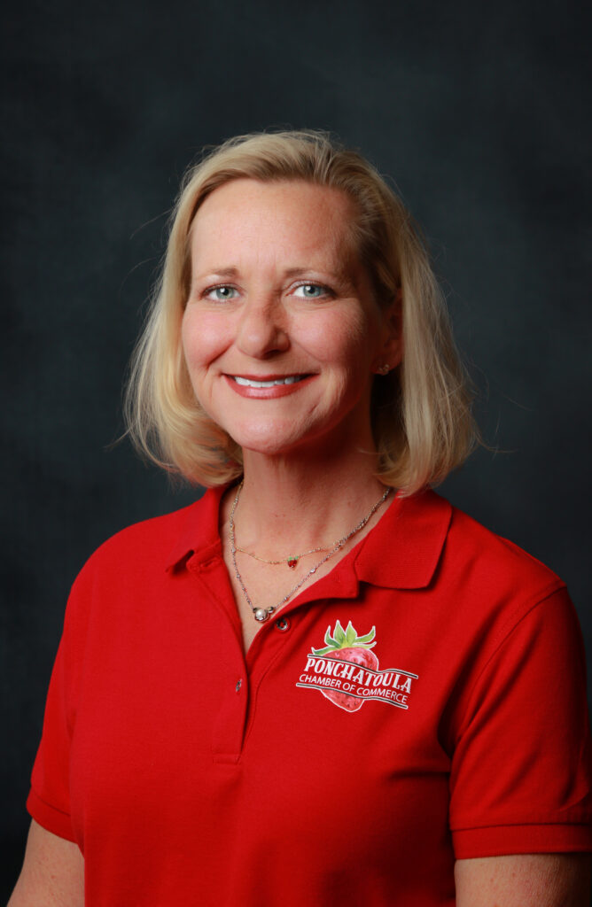 Portrait of a smiling blonde woman in a red polo shirt with a Ponchatoula Chamber of Commerce logo on the chest.