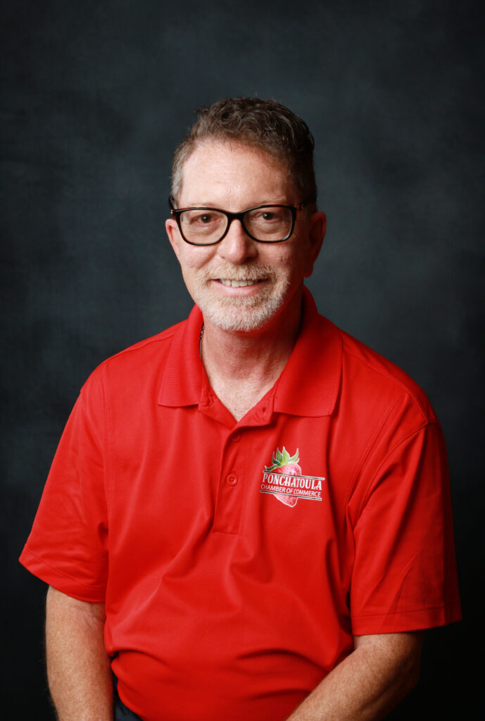Portrait of a smiling man with glasses in a red polo shirt featuring a Ponchatoula Chamber of Commerce logo on the chest.
